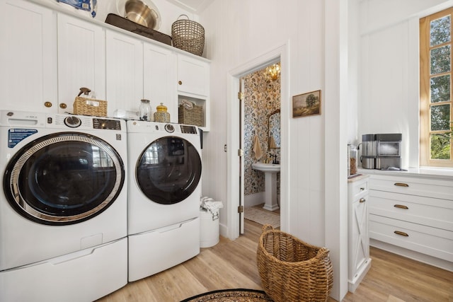 laundry area with cabinets, a wealth of natural light, separate washer and dryer, and light wood-type flooring