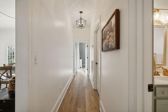 hallway featuring sink, hardwood / wood-style flooring, and a notable chandelier