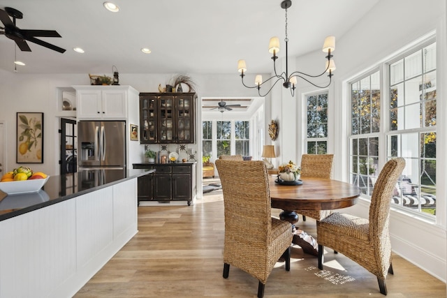 dining space featuring ceiling fan with notable chandelier and light wood-type flooring