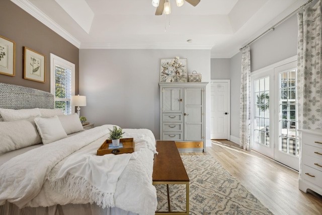 bedroom with ceiling fan, a tray ceiling, access to exterior, and light wood-type flooring