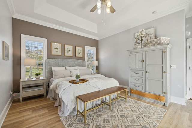 bedroom with ceiling fan, light hardwood / wood-style floors, and a tray ceiling