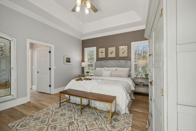 bedroom with crown molding, light hardwood / wood-style flooring, and a raised ceiling