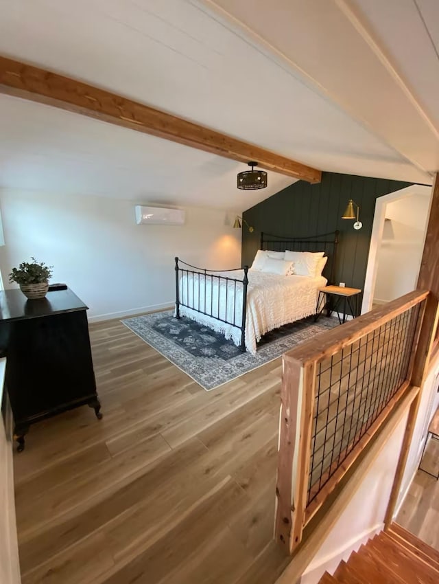 bedroom with lofted ceiling with beams, hardwood / wood-style floors, and a wall unit AC