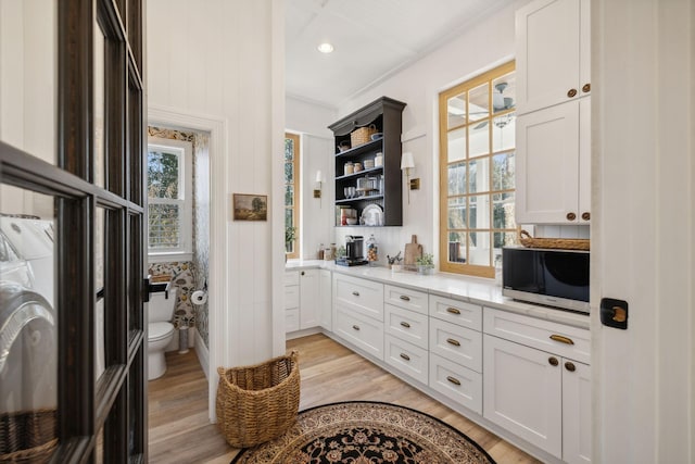 interior space with white cabinetry, light stone counters, and light hardwood / wood-style flooring