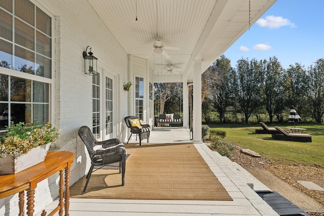 wooden deck with a porch, a yard, and ceiling fan