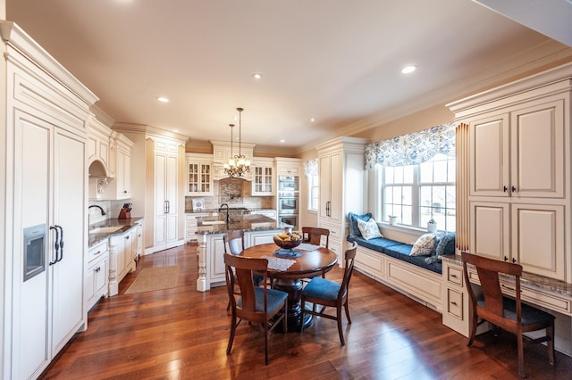 dining space featuring ornamental molding, dark wood-type flooring, sink, and a notable chandelier