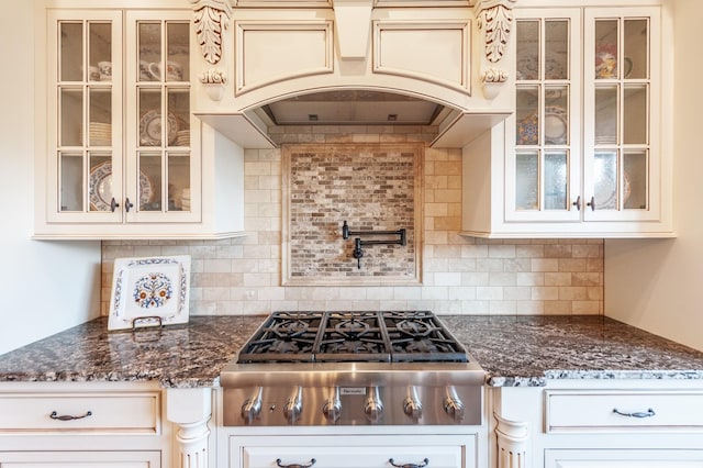 kitchen featuring premium range hood, stainless steel gas cooktop, tasteful backsplash, and dark stone countertops