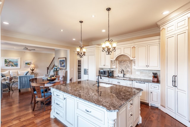 kitchen with dark hardwood / wood-style flooring, sink, decorative light fixtures, and a kitchen island with sink