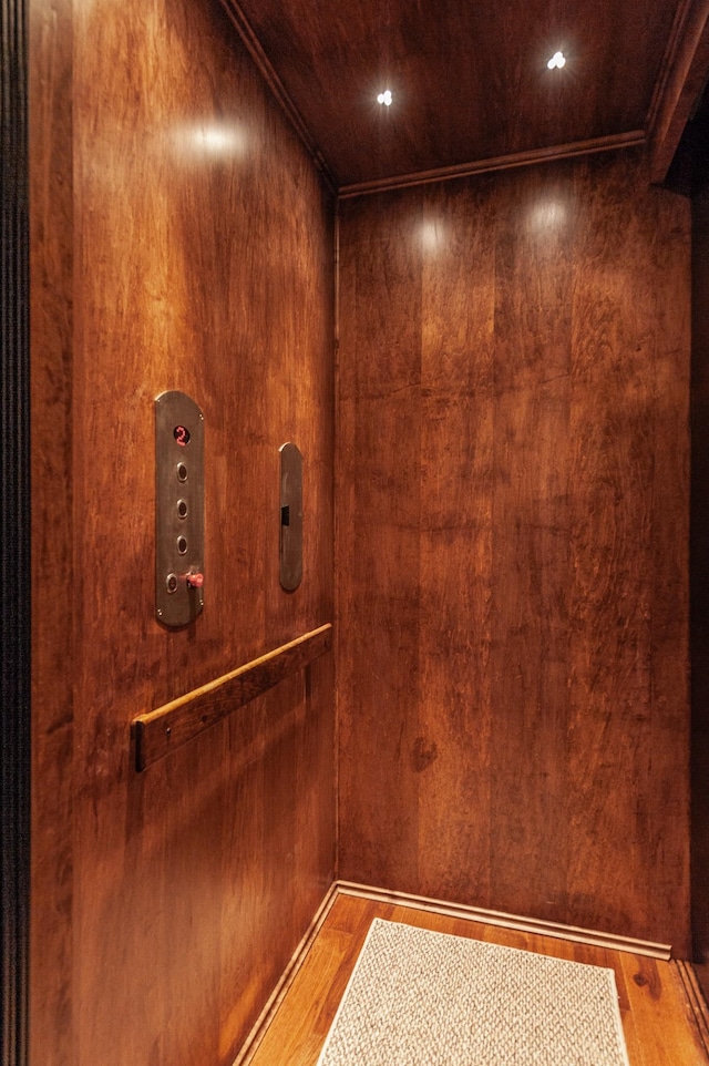 room details featuring hardwood / wood-style floors, elevator, and wooden walls