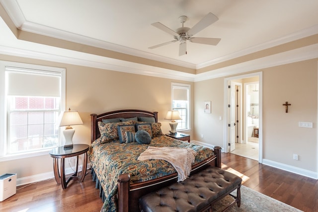 bedroom with multiple windows, crown molding, wood-type flooring, and a raised ceiling