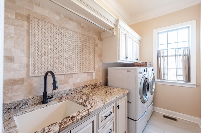 clothes washing area featuring cabinets, washing machine and dryer, sink, and crown molding