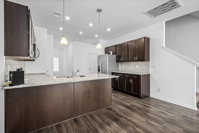 kitchen with light stone counters, hanging light fixtures, sink, and appliances with stainless steel finishes