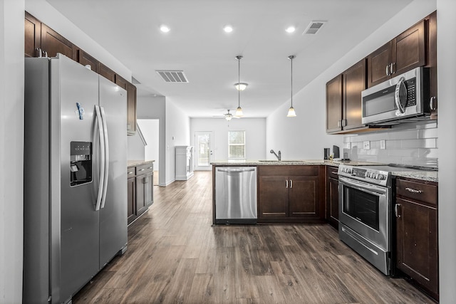 kitchen with dark wood-type flooring, sink, decorative light fixtures, appliances with stainless steel finishes, and kitchen peninsula