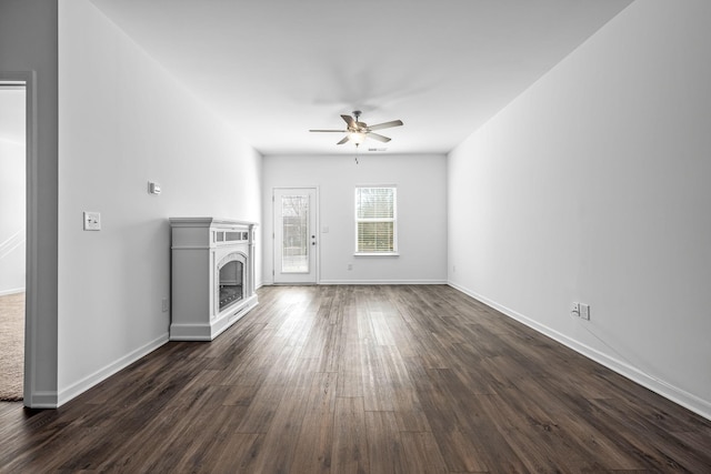 unfurnished living room with dark hardwood / wood-style flooring and ceiling fan