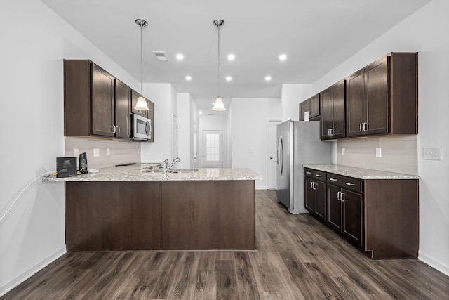 kitchen with dark brown cabinetry, hanging light fixtures, light stone counters, and kitchen peninsula