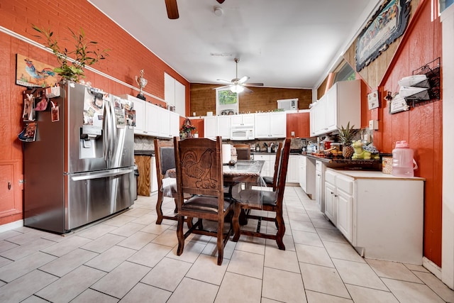 kitchen with backsplash, stainless steel fridge, white cabinets, and vaulted ceiling