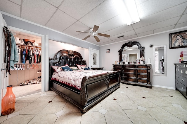 bedroom with a drop ceiling, ornamental molding, ceiling fan, and light tile patterned flooring