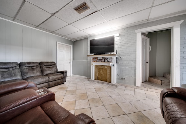 tiled living room featuring brick wall and a paneled ceiling