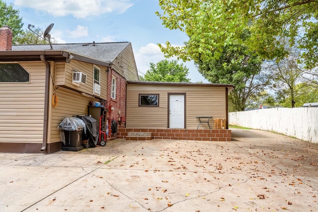 rear view of house with an AC wall unit and a patio area