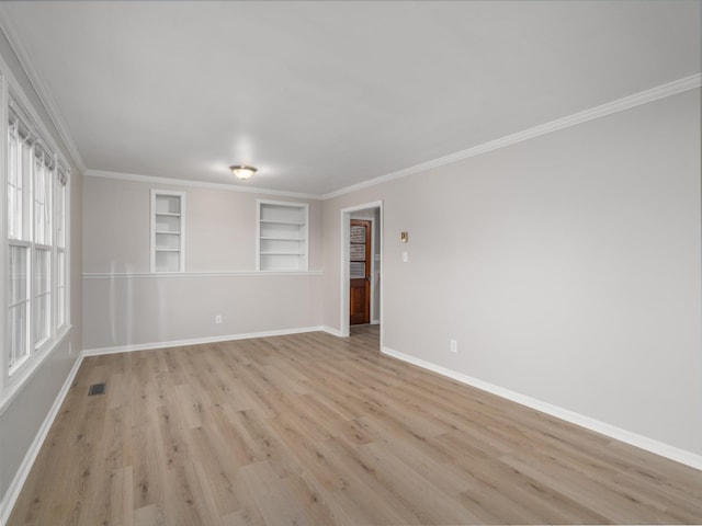 spare room with ornamental molding, built in shelves, and light hardwood / wood-style flooring