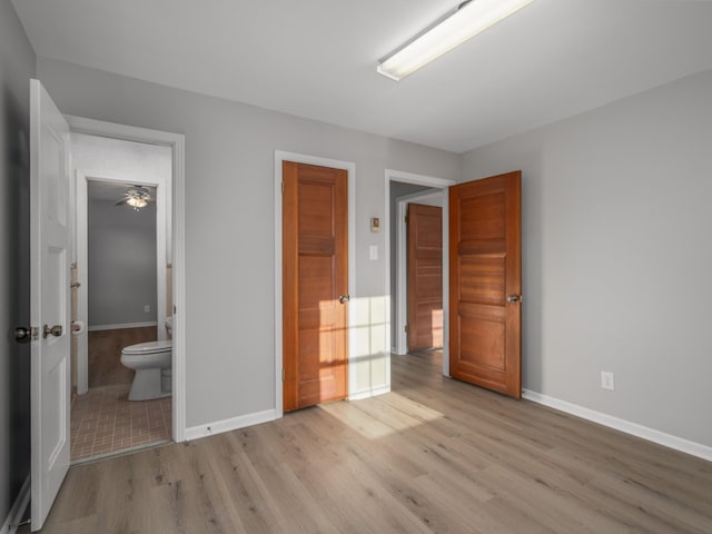 unfurnished bedroom with ensuite bathroom and light hardwood / wood-style floors