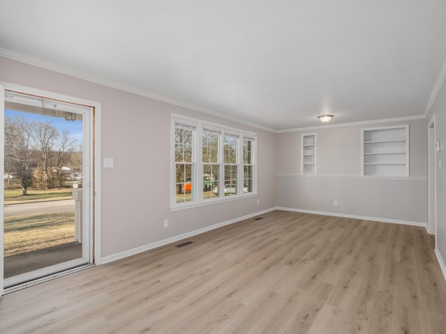 unfurnished room with crown molding, built in shelves, and light hardwood / wood-style flooring