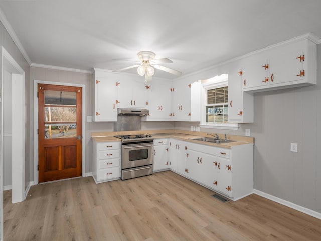 kitchen featuring stainless steel gas range, sink, white cabinetry, light hardwood / wood-style flooring, and ornamental molding