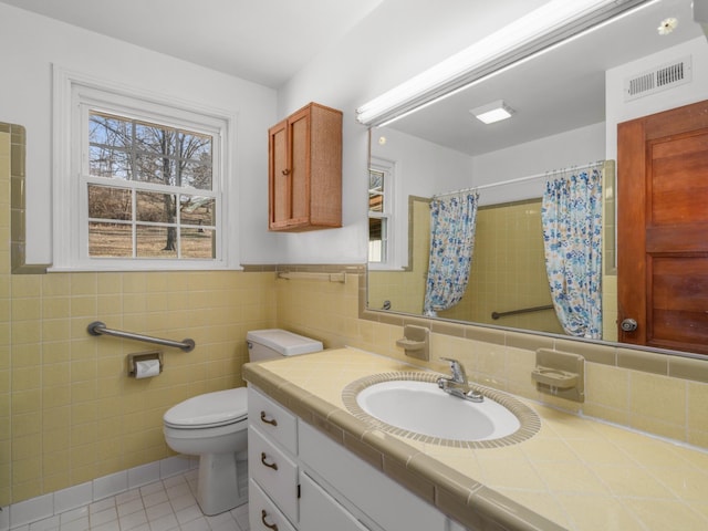 bathroom featuring tile patterned floors, a healthy amount of sunlight, tile walls, and vanity