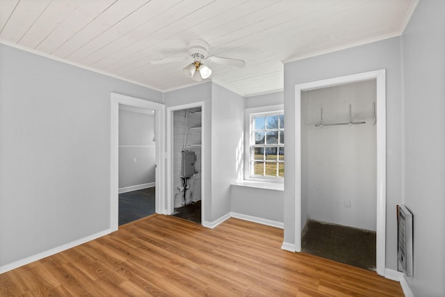 unfurnished bedroom featuring wooden ceiling, ornamental molding, light hardwood / wood-style flooring, and two closets