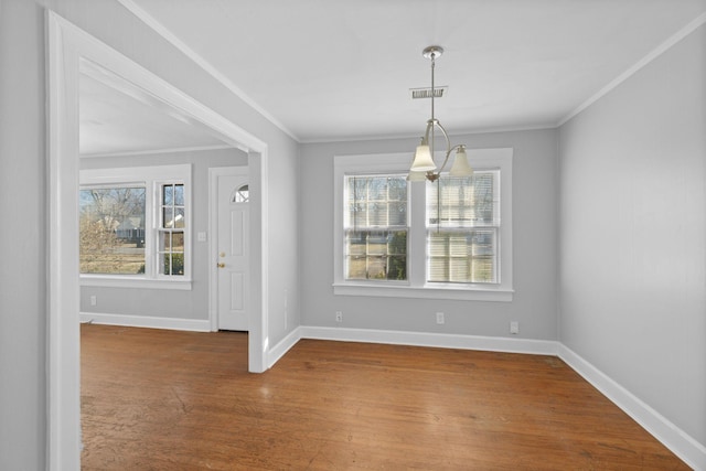 unfurnished dining area with hardwood / wood-style floors, crown molding, and a chandelier