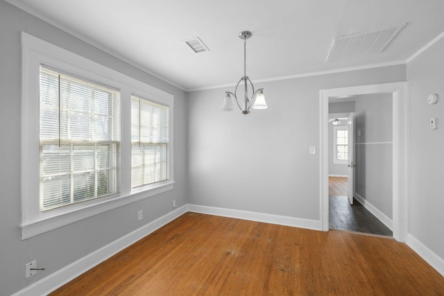 unfurnished dining area featuring ornamental molding, hardwood / wood-style floors, and a notable chandelier