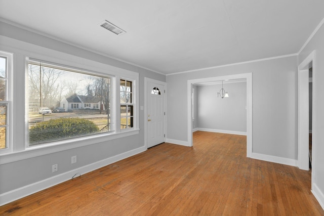 spare room featuring crown molding, an inviting chandelier, and hardwood / wood-style floors