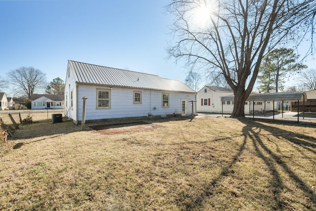 back of house featuring cooling unit, a yard, and a carport