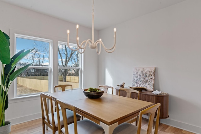 dining space with light wood-type flooring and an inviting chandelier