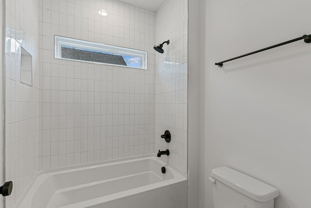 bathroom featuring toilet and tiled shower / bath combo