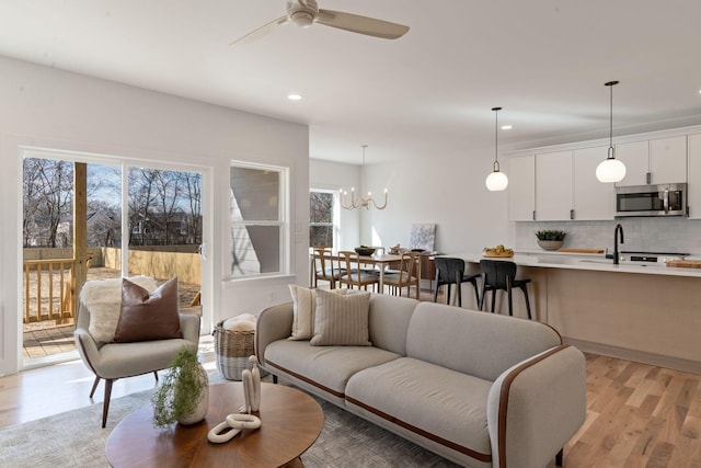 living room with ceiling fan with notable chandelier and light hardwood / wood-style floors