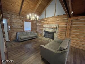 living room with wood ceiling, dark hardwood / wood-style flooring, rustic walls, and beamed ceiling