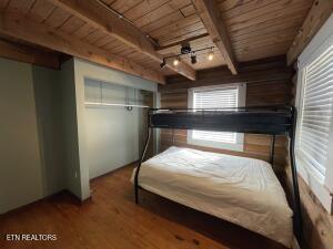 unfurnished bedroom featuring track lighting, wood-type flooring, beam ceiling, and wooden ceiling