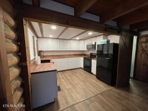 kitchen featuring white cabinetry, stove, black refrigerator, and light wood-type flooring