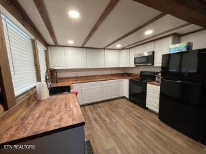 kitchen featuring white cabinetry, light hardwood / wood-style floors, and black appliances