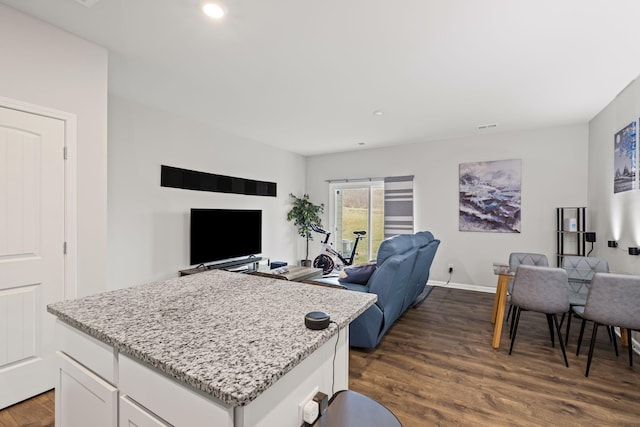 kitchen featuring white cabinetry, a kitchen island, light stone counters, and dark hardwood / wood-style flooring