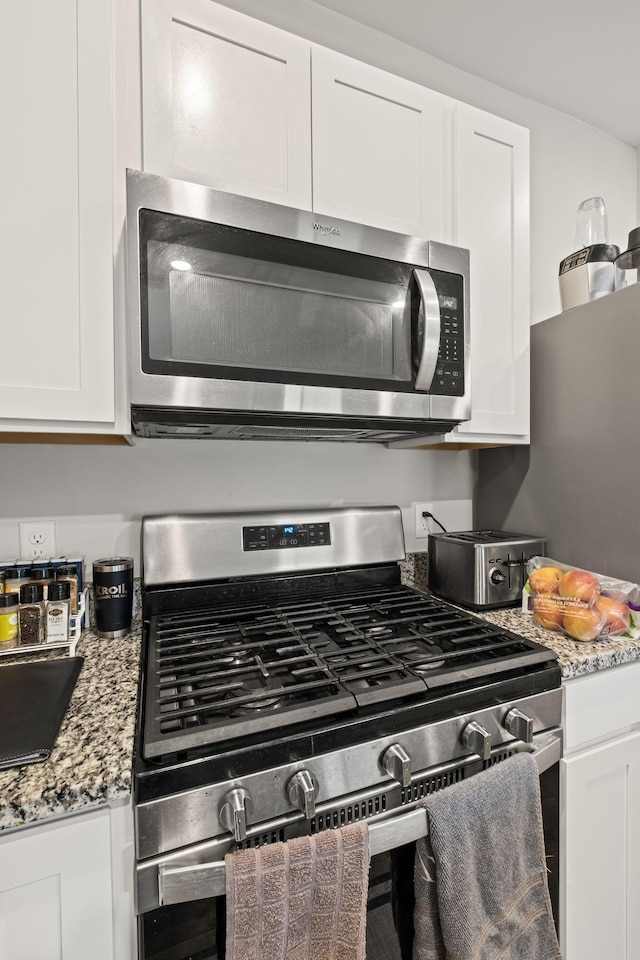 kitchen featuring appliances with stainless steel finishes, light stone countertops, and white cabinets