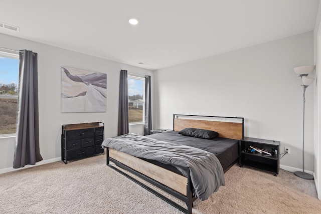 bedroom with multiple windows and light carpet