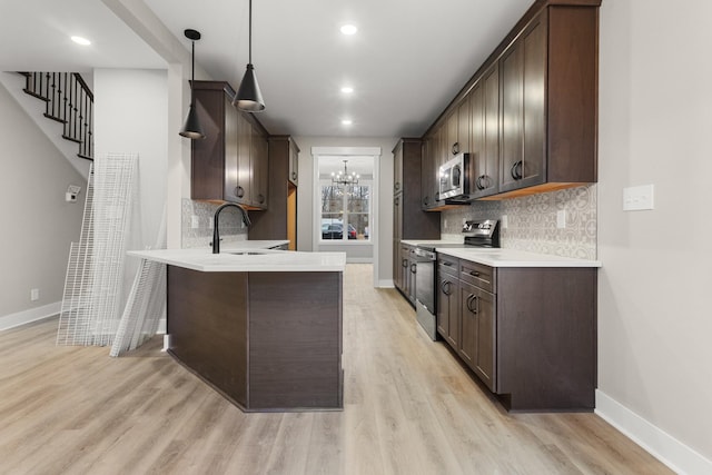 kitchen featuring a peninsula, appliances with stainless steel finishes, dark brown cabinets, and a sink