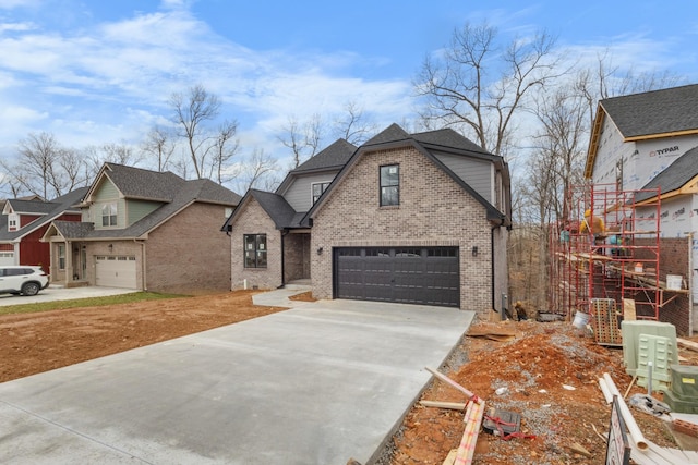 view of front of house with driveway, roof with shingles, a garage, and brick siding