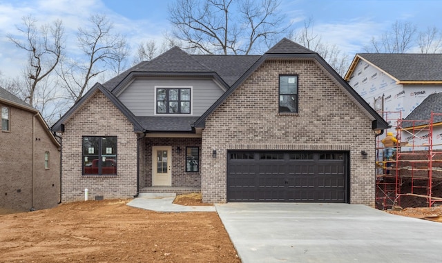 view of front of home featuring a garage, driveway, brick siding, and roof with shingles