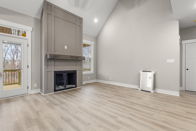 unfurnished living room with light wood-type flooring, a fireplace, and baseboards