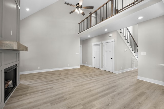 220 Birnam Wood Trce, Clarksville, TN 37043 - unfurnished living room with a towering ceiling, a ceiling fan, baseboards, a large fireplace, and stairway