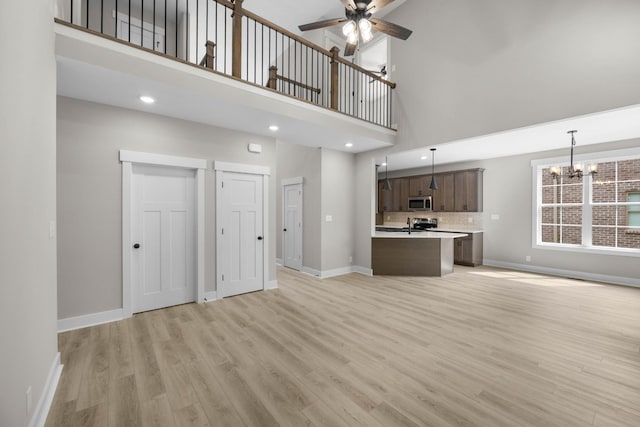 220 Birnam Wood Trce, Clarksville, TN 37043 - unfurnished living room with baseboards, ceiling fan, a high ceiling, light wood-style flooring, and a chandelier