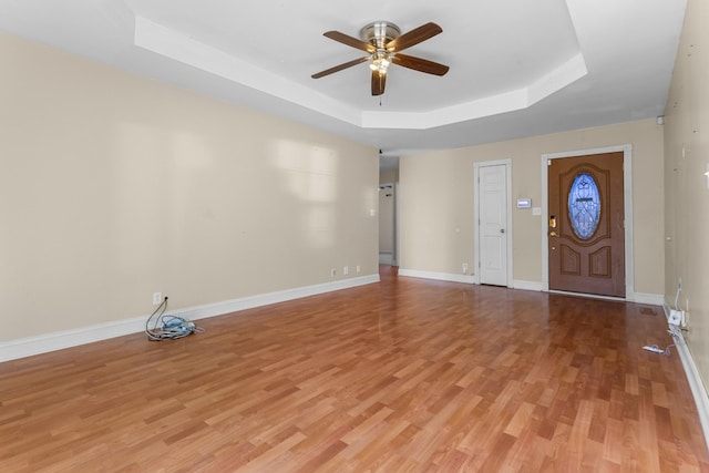 entryway with a tray ceiling, light hardwood / wood-style flooring, and ceiling fan